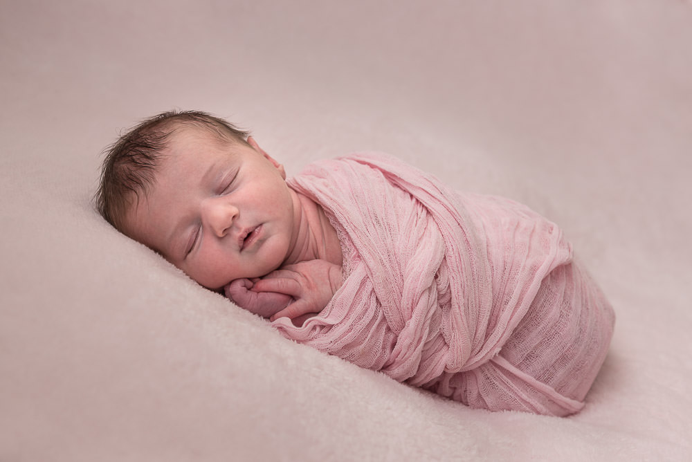 Newborn Baby Girl Wrapped in pink professional studio portrait